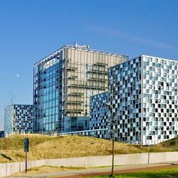 Die drei Quben mit Glasfassade des modernen Gebäudes des Internationalen Stafgerichtshofs in Den Haag, im Vordergrund die Sandsünden, blauer, wolkenloser Himmel.