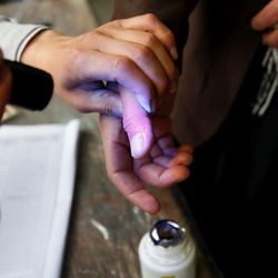 Ein Mann leuchtet auf die Hand einer Frau, bevor sie einen Fingerabdruck abgibt.