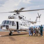 Mehrere Personen laufen auf einen rotierenden Hubschrauber zu