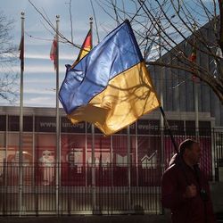 Friedensprotest vor dem UN-Hauptquartier in New York. Ein Mann hält eine ukrainische Flagge in der Hand, im Hintergrund sieht man das UN-Hauptquartier in New York.