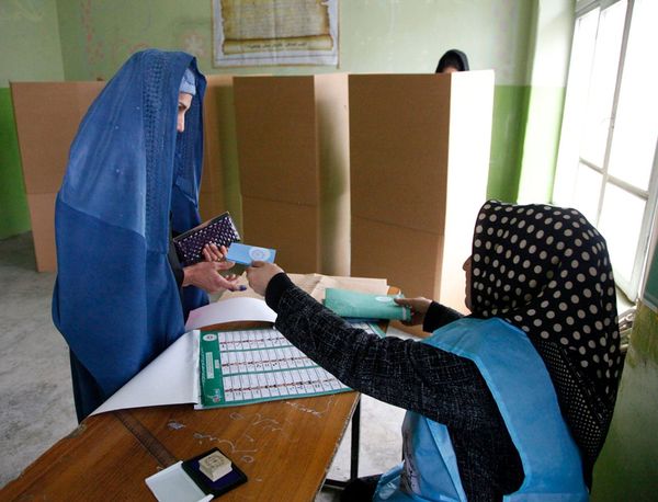 Eine Frau nimmt in einem afghanischen Wahlbüro ihre Wahlunterlagen entegegen.