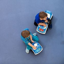 Luftansicht auf zwei Kinder, die auf Spielzeugautos sitzen