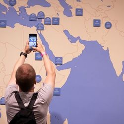 Ein Mann fotografiert mit seinem Handy eine Karte mit den UN-Friedensmissionen.