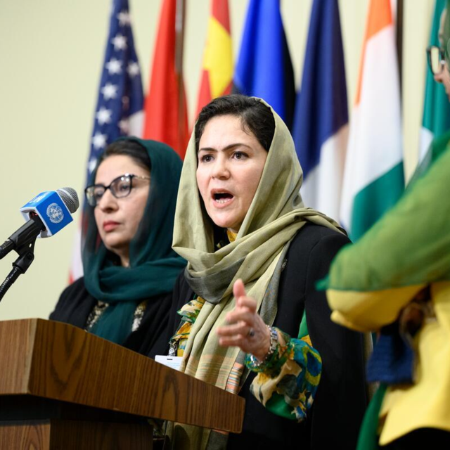 Drei Frauen stehen an einem Pult und sprechen zu Vertretern der UN.