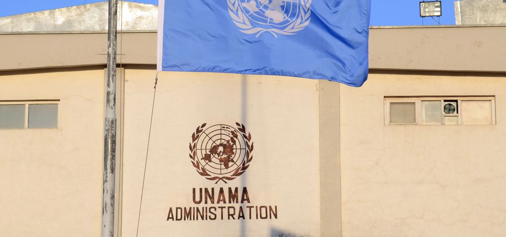 Die Flagge der Vereinten Nationen auf Halbmast vor einem schlichten Gebäude.